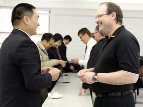 Delegates of Nanjing Agricultural University in China make their first visit to the University of Guelph Ridgetown Campus Thursday, May 23, 2013, in Ridgetown, Ont., as part of their two-day exploration into the creation of a research and development centre of excellence between the two universities. Nanjing Agricultural University dean Jie Chen, left, is welcomed by Ridgetown Campus director Ken McEwan as delegates and hosts exchange business cards. VICKI GOUGH/ THE CHATHAM DAILY NEWS/ QMI AGENCY