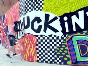 Matthew Brackett, 21, puts the final touches on his 1980's British Invasion inspired graffiti artwork on the hoarding wall enclosing the 1952 double-decker bus in the King Street Commons Friday. DIANA MARTIN/ THE CHATHAM DAILY NEWS/ QMI AGENCY