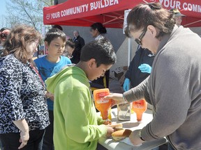 Bev, a volunteer with the RCMP's Citizens on Patrol program, metes out the ketchup at the COPP BBQ on Thursday at the Portage Co-op River Road gas bar. The charity barbecue, which will donate its proceeds to Scouts Canada and the Chance 2 Camp program, was especially popular with students from Ecole Arthur Meighen School. (CLARISE KLASSEN/PORTAGE DAILY GRAPHIC/QMI AGENCY)