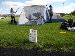 Allison Smith (left) and Dylan Walker struggle to put up a giant tent in the face of strong winds at Assumption College Friday night. (SUSAN GAMBLE, The Expositor)