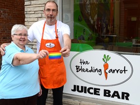 Joan Beecroft and The Bleeding Carrot owner Jim Ansell hold up a "positive spaces" decal in front of Ansell's business in downtown Owen Sound. (DENIS LANGLOIS)