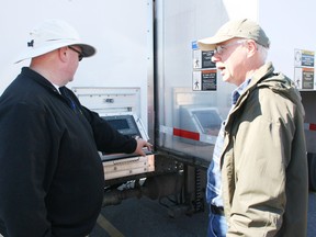James Danyluk of Integra Document Destruction Inc., left, shows Woodstock resident Barry Schneider how the large portable shredder inside one of the company's trucks works during an identity theft awareness event run by CrimeStoppers Oxford and Integra at the Foodland plaza in Woodstock on Saturday, May 25, 2013. JOHN TAPLEY/INGERSOLL TIMES/QMI AGENCY
