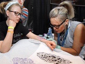 Natasha Nolin tattoos Alicia Dusseault at the Eye of the Lotus booth during the Alberta Bound Tattoo and Arts Festival at the River Cree Casino, in Edmonton, Alta. on Sunday May 26, 2013. David Bloom/Edmonton Sun/QMI Agency