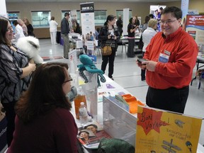 Brant County library assistant Michael Rutledge chats with Genevieve Kwant, Brantford Public library manager of children's and popular services, and outreach co-ordinator Sheila Wiggins. The two libraries had booths at the Making Brantford Brant My Home fair held at Lions Park Arena on Saturday. (HUGO RODRIGUES, The Expositor)