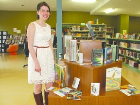 Brianne Sakowich poses with some of the books available during the summer reading program.