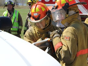 Northern College pre-firefighting students work at ripping open a pickup truck as part of training on how to rescue victims of auto crashes.