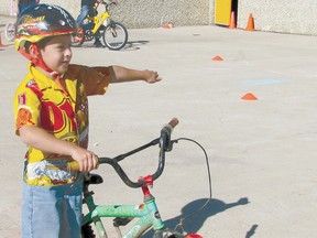 Austin Paupst, a student in the Grade 1 class of teacher Leanna Hagman, demonstrates signalling a left turn. at the bike rodeo held at the basketball court behind Elmer Elson Elementary School in Mayerthorpe on Tuesday, May 21. Mayerthorpe Family and Community Support Services, victim services,  Mayerthorpe and Lac Ste. Anne County community peace officers and RCMP got together to teach kindergarten to Grade 5 students, to help them ride safely.