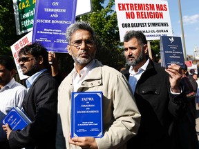 Members of the Muslim group Minhaj-ul-Quran hold up books calling for a fatwa against suicide bombers on Monday in Woolwich, England, where British soldier Lee Rigby was killed by men who told bystanders they act was revenge the deaths of Muslim men at the hands of the British military.