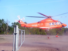 An Ornge air ambulance helicopter kicks up some dust as it lands at a temporary helipad on Bethel Lake Court on Monday evening for the first time. Helicopters are expected to begin flying in and out of the field  for six to eight weeks while the permanent helipad at Ramsey Lake Health Centre is repaired. GINO DONATO/THE SUDBURY STAR