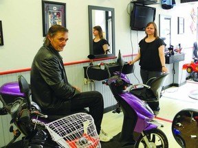 Chris Simpson sits on an E-bike while his his partner Brenda Steacy stands ready by her barber's chair. Simpson and Steacy are the owners of the Sports Cuts Barber Shop in downtown Gananoque.   Wayne Lowrie - Gananoque Reporter