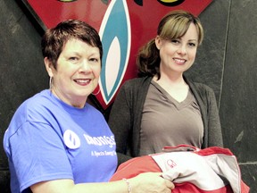 Lynda Anderson, administrative assistant of regulatory affairs for Union Gas, hands Amanda Chartrand, executive assistant for the United Way of Chatham Kent, one coat out of almost 400 pieces of clothing that Union Gas donated to United Way for Operation Cover-Up on Tuesday, May 28, 2013. The clothing will be provided to less fortunate families in Chatham-Kent.  KIRK DICKINSON/FOR CHATHAM DAILY NEWS/ QMI AGENCY