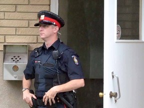 Stratford Police Const. Rob McMillan keeps a watch across a courtyard to the scene at 333 Home St. apartments Wednesday morning. (SCOTT WISHART The Beacon Herald)