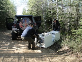 Members of the True North Trailrunners pull a washer and dryer from the wooded areas of Sand Lake, Saturday, May 25. (Photo: Ted Ingram/TNT)
