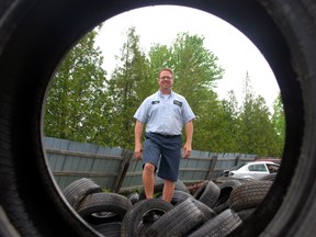 Jeff McGregor stands atop a pile of used tires at McGregor Auto Parts, the Elm Street business he co-owns with brother Tim. The McGregors are collecting used tires now through Saturday to raise money for the Sunshine Foundation.
