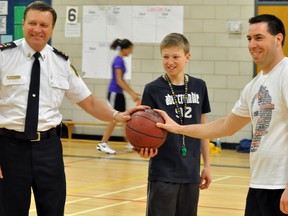 R. Ross Beattie Senior Public School principal Al McLean, right, along with students and staff, faced Timmins Police Service in a charity basketball game earlier this week. School liaison officer Const. Bill Martin, left, organized the game, which also supporter the Timmins Food Bank. Grade 7 student Justin McDowell acted as coach, tossing the jump ball between the two to get the game going.