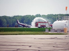 Central Elgin firefighters spray a bed of flame retardant foam around a small airplane that was forced to make an emergency landing Thursday afternoon at the St. Thomas airport. The pilot completed the landing after confirming his front landing gear was out of position. The plane never caught fire and the pilot suffered a minor injury but refused medical attention and was not taken to hospital, according to EMS duty manager Bernie Bakker. (Ben Forrest, Times-Journal)