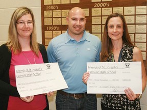 Kathy Cepo, left, receives a $1,500 donation to the robotics program and Luci Clark, right, receives a $3,000 donation to the drama program from Chris Willemse, treasurer of The Friends of St. Joseph’s. The group's annual golf tournament helps fund such gifts. CONTRIBUTED