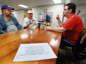 A laminated dinner prayer sheet lies on the table in front of OSHaRE soup kitchen patrons, from left, Brian Ball, Steve Treleaven and John Murphy as they chat over dinner at the former Knox United Church in Owen Sound on Friday. James Masters The Sun Times