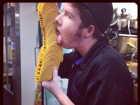 A Taco Bell employee is seen licking taco shells in this photo posted to the company's Facebook page. (Facebook)
