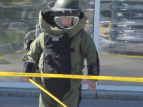 Still clad in his protective gear, an officer with the OPP's bomb disposal unit uses a grabbing tool to pick up possible pieces of evidence after the suspicious package had been blown apart.
Michael Lea The Whig-Standard
