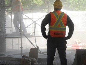 A cloud of sand lingers as construction worker Tony Hopkins of Mclean Taylor Limited sandblasts one of 17 columns that are under repair on the Donohue Bridge. The overpass is undergoing substructure repairs, as part of a $3.2 million project. Currently, four of the six lanes are closed to traffic to relieve the columns and pier caps of stress while the the cement goes through a curing process. (BLAIR TATE, For the Observer)