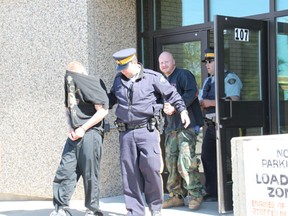 Jesse Welch (left) and James Lawn are escorted by RCMP out of the provincial building in Melfort after making their first court appearance on Monday.