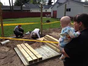 Nicole Sauve holds her granddaughter as police remove human remains from the yard behind her house at 122 Alexandra Avenue in Point Edward. The remains will be sent off today for forensic testing. (TARA JEFFREY, The Observer)