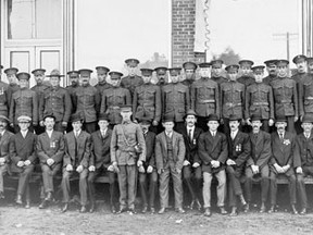 A contingent of Kenora soldiers with the 98th Infantry Regiment, the local militia unit, new recruits and South African War veterans pose for a group photograph in front of the Vereker Block on Matheson Street in Kenora in November 1914.