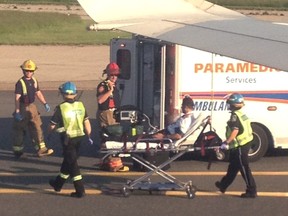 Photo courtesy Dave Brown showing an Air Canada pilot being removed from a flight from Calgary, Alta to Newark, New Jersey on May 30, 2013. The flight was diverted and landed in Toronto, ON where the pilot had an emergency and after landing was met my paramedics. Dave Brown handout/Calgary Sun