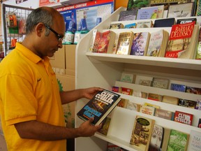 Bob Pate, owner of Ritu's Convenience and Foodmart browses through the books left at the small lending library located at his store.  (TARA BOWIE, Sentinel-Review)