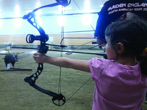 A young girl tries her hand at archery.