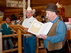 Farley Wuth holds a copy of 'Prairie pass to mountain grass' at the auction of the first press copy. File Photo.