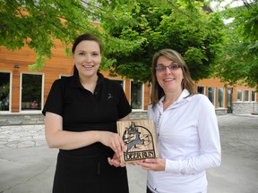 Lori Gall, executive director of New Beginnings, right, presents a plaque to Larissa LeGros, of Deer Run Golf Course, on Friday. Gall said the organization wanted to recognize the business' actions after a fire last year, allowing her organization to hold its annual fundraising golf tournament. (TREVOR TERFLOTH, Daily News)