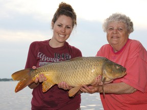 Ashley Rae assists her grandmother, Bette Rae, with her first carp, a 15-pounder caught and released in the Napanee River. (Supplied photo)