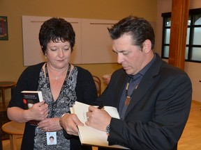 Former NHL star Theo Fleury signs his book as Cindy Wheeler, senior fund development officer with Bruce Grey Child and Family Services Foundation, looks on before Fleury spoke at a fundraiser at the CAW Centre in Port Elgin on Friday. (ROB GOWAN The Sun Times)