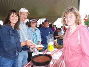 Lynn Kirby, left, Ralph Dyson and Robin Dyson serve rhubarb and ice cream to Diane Bell of London Saturday at Rosy Rhubarb Days in Shedden.