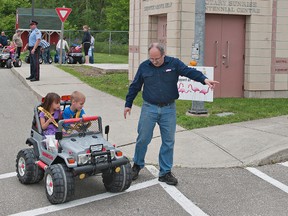 Trevor Eason of Brantford directs his four-year-old daughter, Sierra, and son Derek, 5, as they drive a motorized vehicle at the Children's Safety Village on Saturday during the Kids Street Festival. (Brian Thompson, The Expositor)