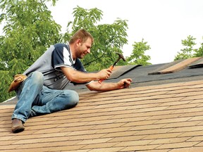 A man nails new shingles into a roof. (Postmedia Network file photo)