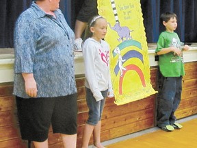 At left, Anna Greenwood, principal of Elmer Elson Elementary School, stands by the school’s stage with students  Kadence Prokipchuk, left, and Zachary Jackson as the school’s students and staff welcome the appointment of Greenwood as principal. Beside them, is a gift to Greenwood, a banner for her office door made by the mothers of Kadence and Zachary, Natasha Prokipchuk and Deanna Jackson.
Ann Harvey | Mayerthorpe Freelancer