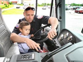 Firefighter John Lazaridis helps Scylla Volbracht, 2 1/2, activate the lights and sirens of a North Bay Fire and Emergency Services truck, during the 12th annual Community Living North Bay Safety Day, at the Ontario Early Years Centre on June 10, 2013. (MARIA CALABRESE The Nugget)
