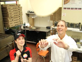 Kelly Toppazzini, CEO of Topper's Pizza, demonstrates his pizza-tossing skills to Kira Timony, district manager of Topper's Pizza. The Sudbury business is featured in Food Network Canada's Giving You the Business. JOHN LAPPA/THE SUDBURY STAR/QMI AGENCY