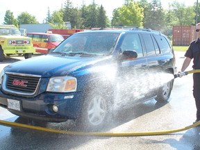 A car wash to conquer cancer was held at the Kincardine Firehall on June 8, 2013 to raise money for the Princess Margaret Cancer Centre. Firefigher Mike Drake helped wash cars with the fire hose. (ALANNA RICE/KINCARDINE NEWS)