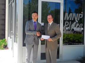 Patrick Rae of RBC Dominion Securities Inc. presents a cheque for $1,000 to Lou Antonissen of the Community Foundation of Portage and District (CFPD), Tuesday, in front of MNP Place. The funds will go to the grant making program which will in turn support an initiative for children in need. (ROBIN DUDGEON/PORTAGE DAILY GRAPHIC/QMI AGENCY)