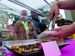 Paul Ruston, centre, and his mother Alison Ruston watch as Heather Rowat, owner of Sweet Fig Bakery, packs some fresh dessert bars at the Prescott Farmers' Market on Tuesday morning. (THOMAS LEE/The Recorder and Times)