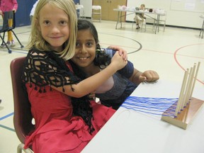 Students at Kincardine Township Tiverton Public School took part in a Pioneer Day Tuesday, June 4,2013 as a culmination of the pioneer unit they've been studying in class. Leena Mahoob and Harleen Randlawa are excited to start weaving their own scarves. (AVERY LAFORTUNE/KINCARDINE NEWS CO-OP)