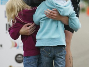 A dad gets hugs from his daughters after completing a past Lake Summerside Triathlon. FILE PHOTO