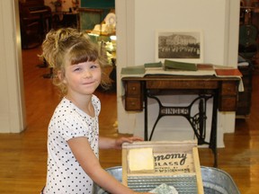 Kiera Klien, 5, tries out the washboard at the Heritage Museum Saturday afternoon.