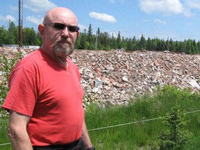 John Fonteine, above, stands in front of the mound of red brick and concrete from the demolition of the former North East Mental Health Centre that has skewed the view from his backyard for several months.