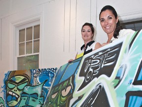 Angela Henrique (left), chair of A Taste of Glenhyrst, and Ana Olson, partnership co-ordinator at Glenhyrst Art Gallery of Brant, show two of the numerous large graffiti art pieces that will be displayed during the annual fundraising event on June 20.(Brian Thompson, The Expositor)