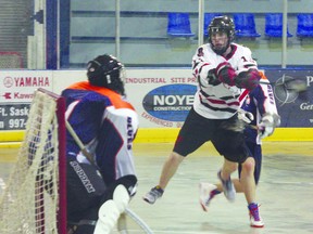 A Fort Saskatchewan Rebels player takes a running jump through the crease as he tries to sneak a shot by the West Edmonton Blues goalie in a lopsided victory for the Rebels. Photo by Aaron Taylor.